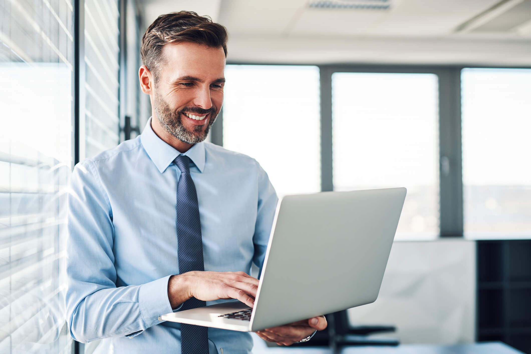 Imagem de um homem do ramo da justiça vestido de roupa social trabalhando feliz em seu laptop